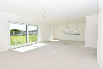 Obývací pokoj se vstupem na zahradu, s jídelním koutem a kuchyně s oknem.  - Prodej domu 211 m², Horoměřice