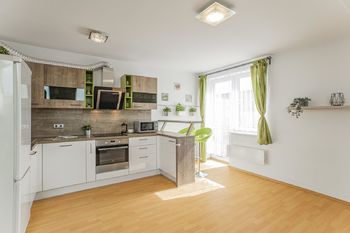 Obývací pokoj s kuchyňskou linkou a vstupem na balkon - Prodej bytu 2+kk v osobním vlastnictví 50 m², Jinočany