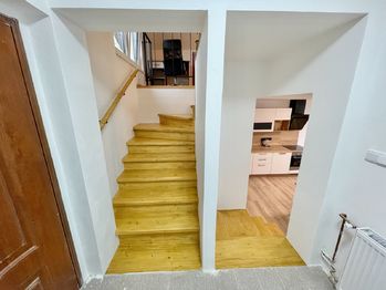 Pohled z chodby na schodiště do patra a do obytné místnosti s k.k. v přízemí - Pronájem bytu 2+kk v osobním vlastnictví 48 m², Řepice