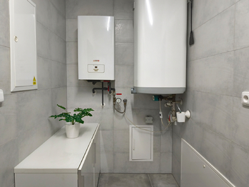 Technická místnost s elektrokotlem, bojlerem, úložnými prostory, výlevkou a místem na pračku a sušičku. - Prodej domu 157 m², Kly