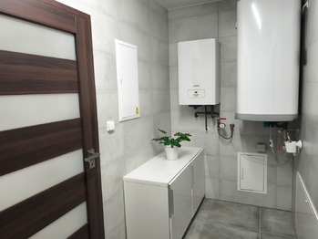 Technická místnost s elektrokotlem, bojlerem, úložnými prostory, výlevkou a místem na pračku a sušičku. - Prodej domu 157 m², Kly