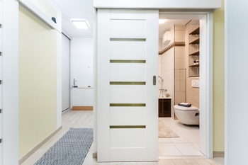 Vstupní chodba s 2x vestavěnou šatní skříní a samostatnou prostornou šatnou - před výmalbou na bílo. - Prodej bytu 2+kk v osobním vlastnictví 52 m², Praha 9 - Hostavice