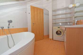 Koupelna s vanou, umyvadlem se skříňkou, zrcadlem, místem na pračku a úložné prostory. - Prodej bytu 3+kk v osobním vlastnictví 82 m², Praha 9 - Čakovice