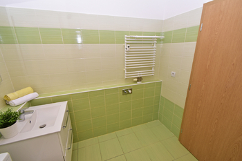 Koupelna s vanou, toaletou, umyvadlem se skříňkou, zrcadlem a místem na pračku a sušičku.  - Pronájem bytu 2+kk v osobním vlastnictví 60 m², Praha 8 - Libeň