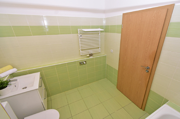 Koupelna s vanou, toaletou, umyvadlem se skříňkou, zrcadlem a místem na pračku a sušičku.  - Pronájem bytu 2+kk v osobním vlastnictví 60 m², Praha 8 - Libeň