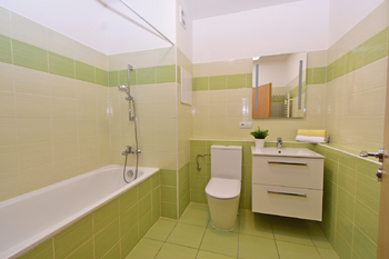 Koupelna s vanou, toaletou, umyvadlem se skříňkou, zrcadlem a místem na pračku a sušičku.  - Pronájem bytu 2+kk v osobním vlastnictví 60 m², Praha 8 - Libeň