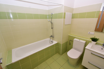 Koupelna s vanou, toaletou, umyvadlem se skříňkou, zrcadlem a místem na pračku a sušičku.  - Pronájem bytu 2+kk v osobním vlastnictví 60 m², Praha 8 - Libeň