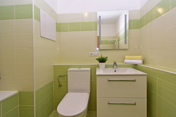 Koupelna s vanou, toaletou, umyvadlem se skříňkou, zrcadlem a místem na pračku a sušičku.  - Pronájem bytu 2+kk v osobním vlastnictví 60 m², Praha 8 - Libeň