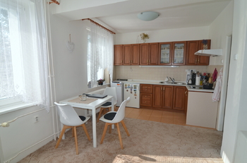 pohled na kuchyňský kout a jídelní stůl se třemi židlemi - Pronájem bytu 1+kk v osobním vlastnictví 37 m², Praha 5 - Zbraslav