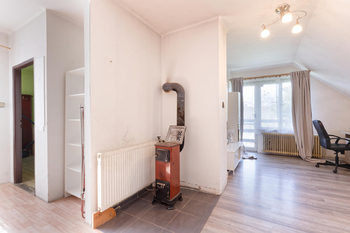 Ve druhé z místností v patře se topí kamny a je tady funkční kuchyň a vstup na balkón - Prodej domu 150 m², Chodouň