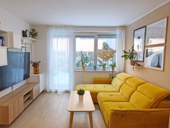 Obývací pokoj se vstupem na terasu a zahradu, jídelní a kuchyňský kout.  - Pronájem bytu 2+kk v osobním vlastnictví 52 m², Praha 9 - Hostavice