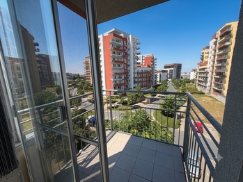 Pohled ze zasklené lodžie, skrze zastřešený balkón. - Prodej bytu 2+kk v osobním vlastnictví 61 m², Praha 9 - Letňany