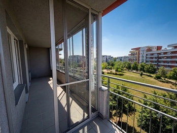 Pohled ze zastřešeného balkónu do zasklené lodžie - aktuální stav. - Prodej bytu 2+kk v osobním vlastnictví 61 m², Praha 9 - Letňany