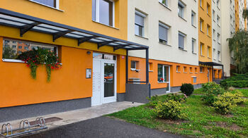 Vchod s přístřeškem do budovy, udržovaná zeleň kolem domu.  - Prodej bytu 5+kk v osobním vlastnictví 109 m², Neratovice